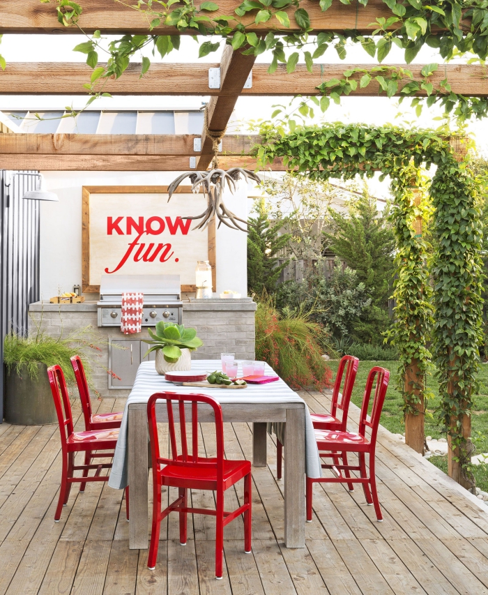 aménager une cuisine de jardin avec gril d'extérieur en acier inoxydable, déco de jardin avec chaises rouges et tableau blanc au cadre bois