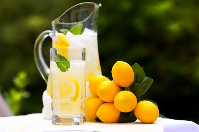 pichet et verre de cocktail rempli de citronnade fraîche à la base d'eau froide glaçons et jus de citron pressé