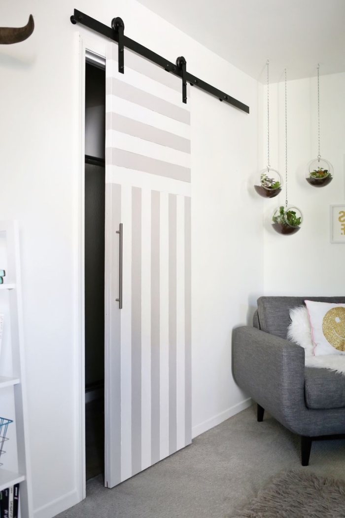 une porte interieure coulissante très pratique pour aménager les petits espaces, qui se fait également un accent déco grâce à ses rayures en peinture blanche et son rail contrastant