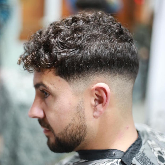 coupe homme rasé coté long dessus avec dégradé arrondi pour cheveux bouclés bruns