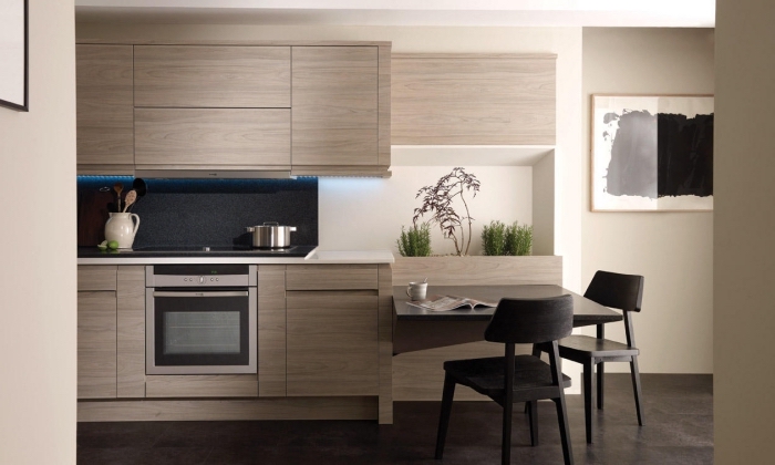 modèle de cuisine tendance aux murs beige et parquet foncé avec meubles de bois gris et crédence noire