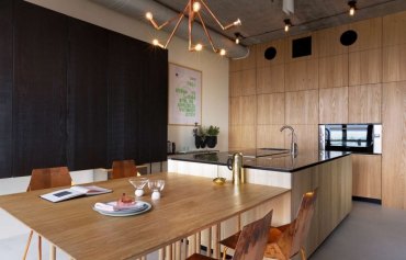 cuisine bois massif pan de mur noir tuyaux apparents style industriel table a manger bois clair armoires sans poignées ilot central bois