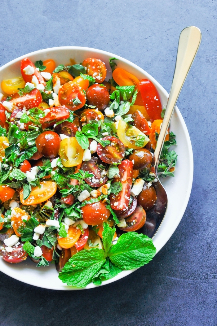 recette méditerranéenne de salade verte composée, de tomates cerises, fromage de feta et d'herbes fraîches comme la menthe, l'origan et le basilic