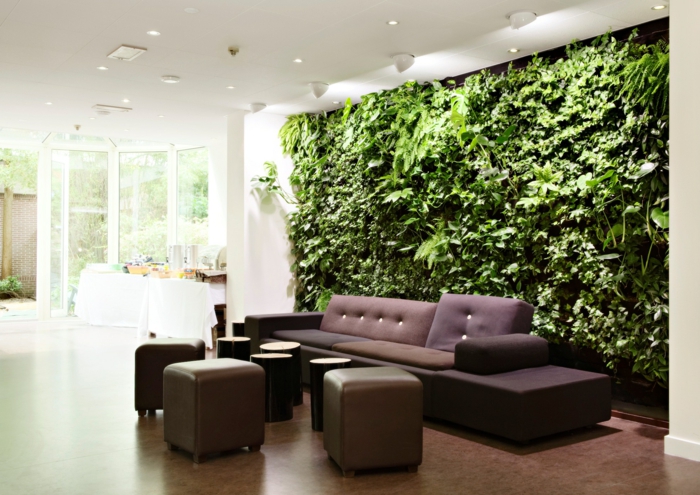 mur végétal intérieur, grand panneau couvrant un grand mur dans un salon aux meubles classiques marrons, sol recouvert de parquet en PVC en marron, plafonniers blancs au plafond