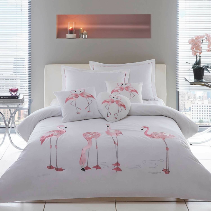 chambre d'adulte, linge de lit blanc avec des flamants roses, grands coussins, tete de lit en blanc, niche murale avec des bougies, mur en gris perle, deco exotique, papier peint flamant rose