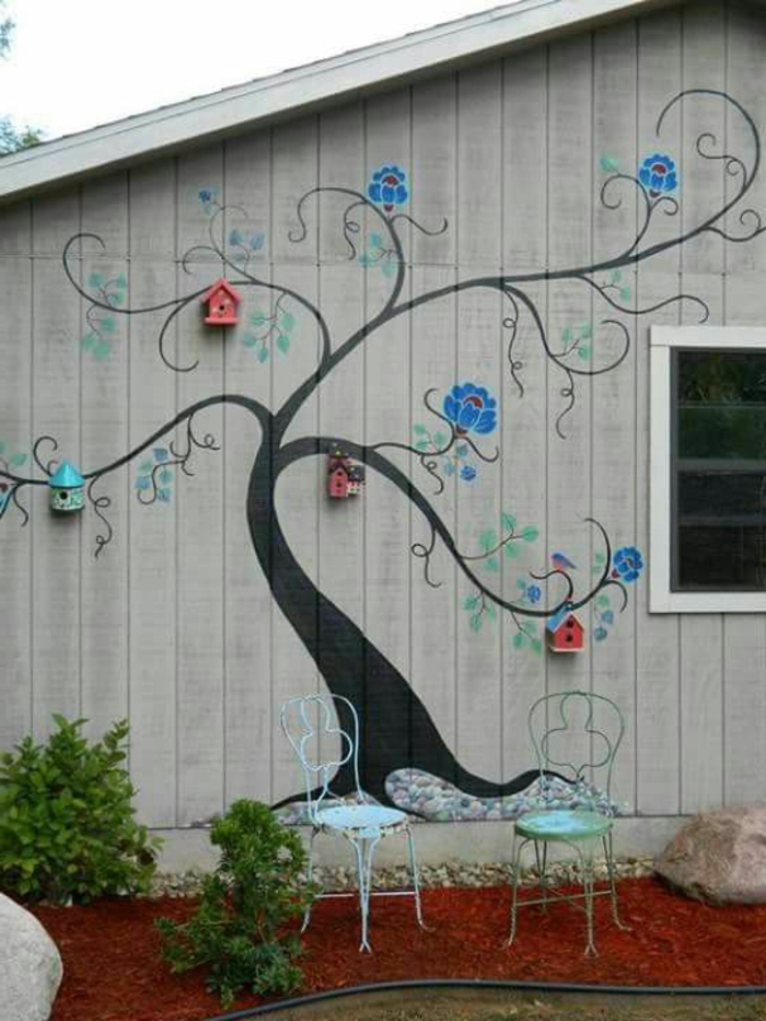 revetement mural exterieur, avec dessin d'arbre noir aux branches ramifiées avec des maisons d'oiseaux aux bouts des branches, quatre maisons d'oiseaux en bois coloré en rouge et bleu pastel 