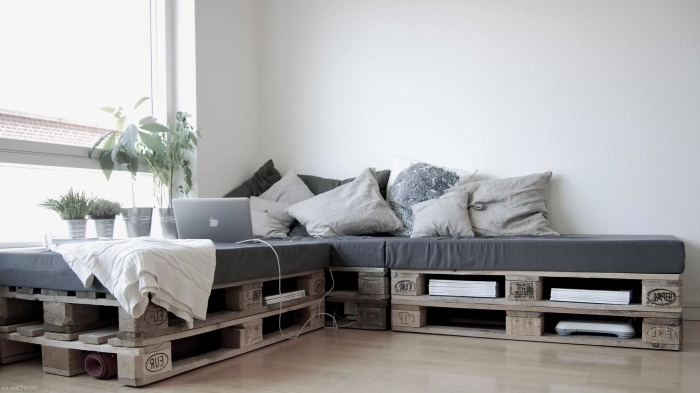 déco de salon minimaliste avec parquet de bois laqué clair et modèle de canapé d'angle en palette diy couvert de coussins