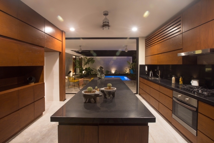 design intérieur cuisine aux murs blancs avec meubles encastrés de bois massif foncé et ilot central en noir et bois brut