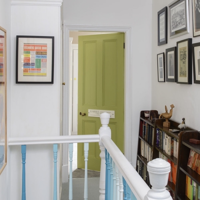 les barreaux d'escalier en dégradés et la porte interieur bois repeinte en vert olive dynamise le couloir blanc