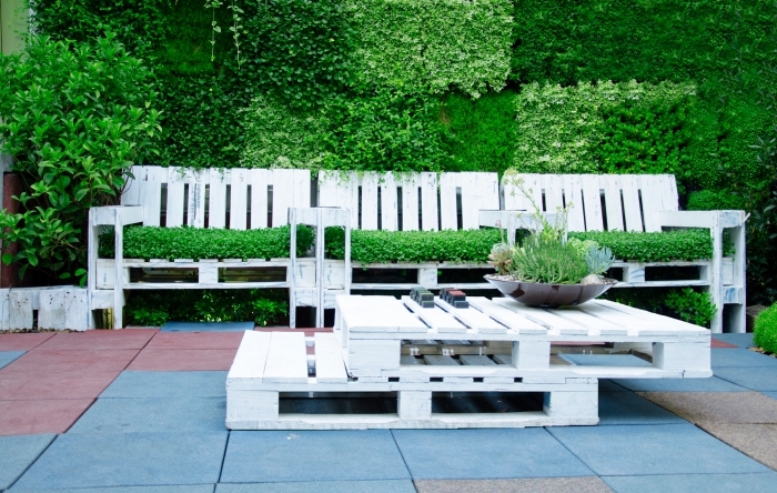 aménagement avec table basse palette et bancs en bois peints en blanc couverts de gazon artificiel vert pour une déco de jardin