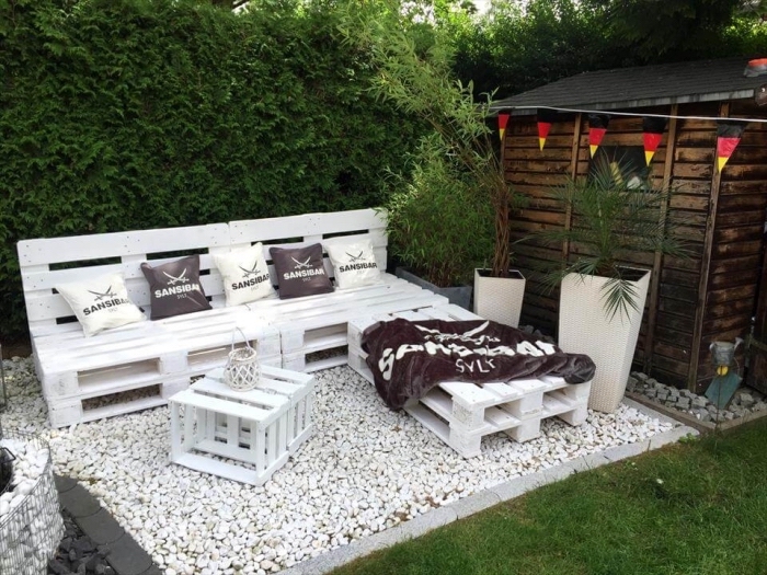 modèle de table basse palette et un canapé en bois peint blanc couvert de coussins décoratifs en blanc et gris