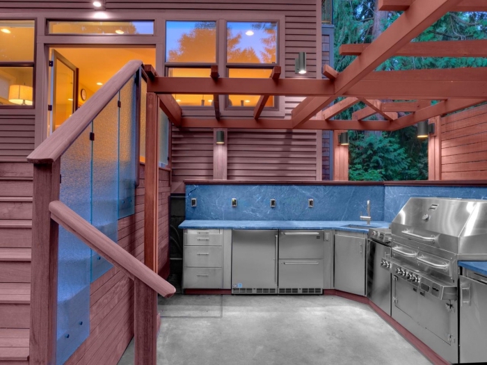 construction de cuisine dans le jardin avec toit en bois et modules en inox et carrelage bleu, modèle de cuisine en L
