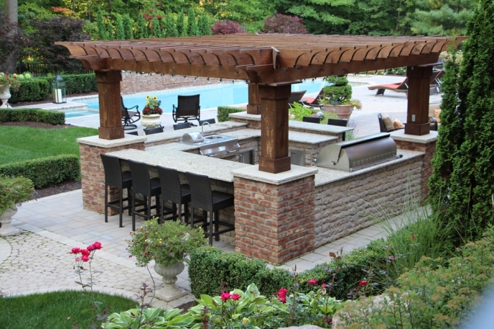 idée comment aménager un jardin avec piscine et coin de cuisine couverte en toit de bois massif et ilot en pierre