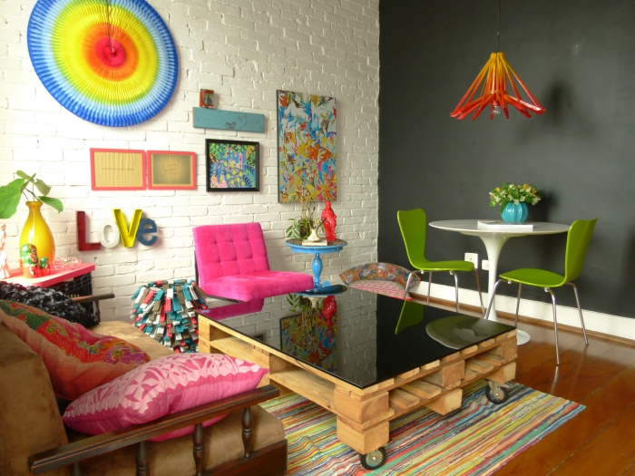 salon éclectique aménagé en style pop art coloré, avec une table basse originale à plateau noir brillant qui s'accorde avec le mur d'accent en ardoise