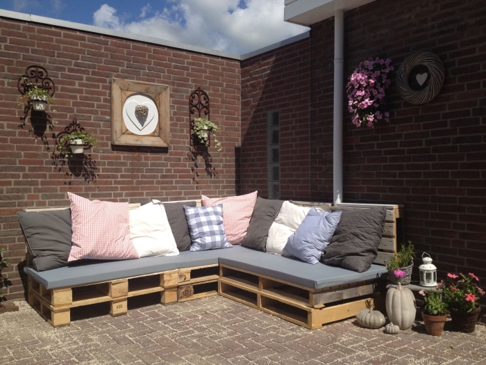 idée pour fabriquer meuble avec palettes de bois couvert de housse siège grise et coussins décoratifs, déco jardin avec canapé d'angle DIY