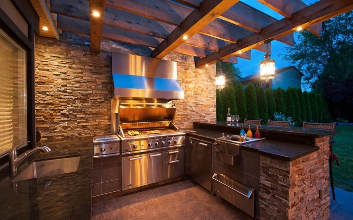 idée pour abri cuisine extérieure avec toit en bois et éclairage led, cuisine d'été avec murs en pierre aménagée en U