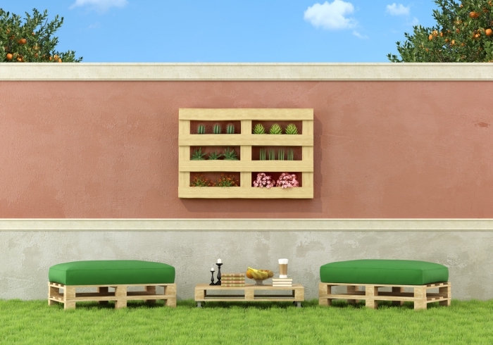 exemple de meubles de jardin en palettes avec deux tabourets à siège vert et une table basse placés sur un gazon vert