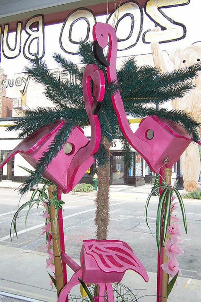 objet deco original sur une vitrine, une famille de flamants en bois peint en fuchsia, deco tropicale dans un magasin, statue flamant rose