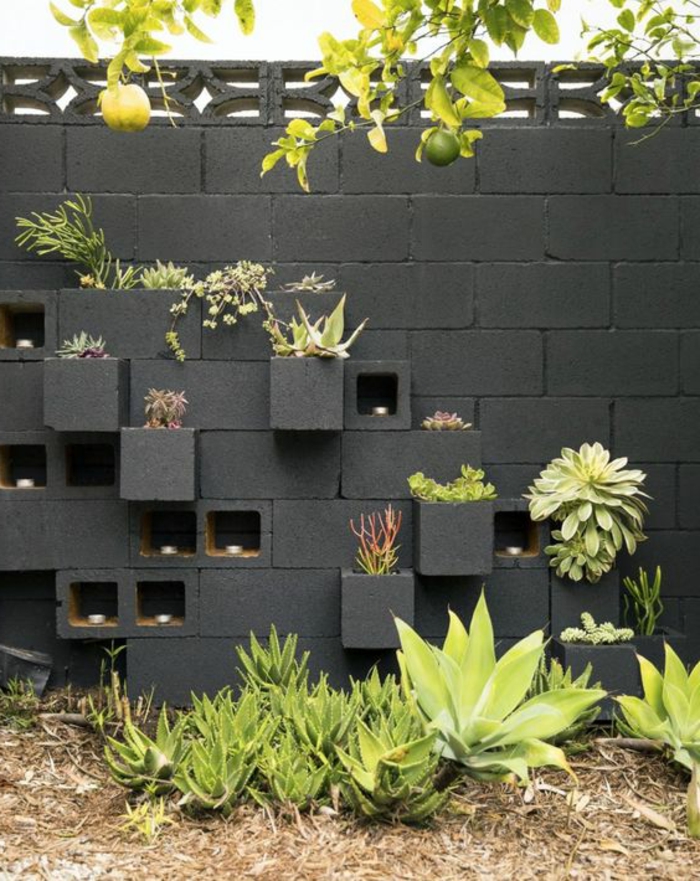 deco mur exterieur, habiller un mur extérieur en pierre en gris anthracite, avec des éléments cubes rentres et sortis du mur effet asymétrique, cubes pleins de plantes vertes, un arbre citronnier