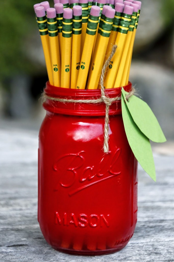pot à crayon imitation pomme rempli de crayons, bricolage avec pot en verre recyclé et repeint en rouge, feuilles de papier vertes