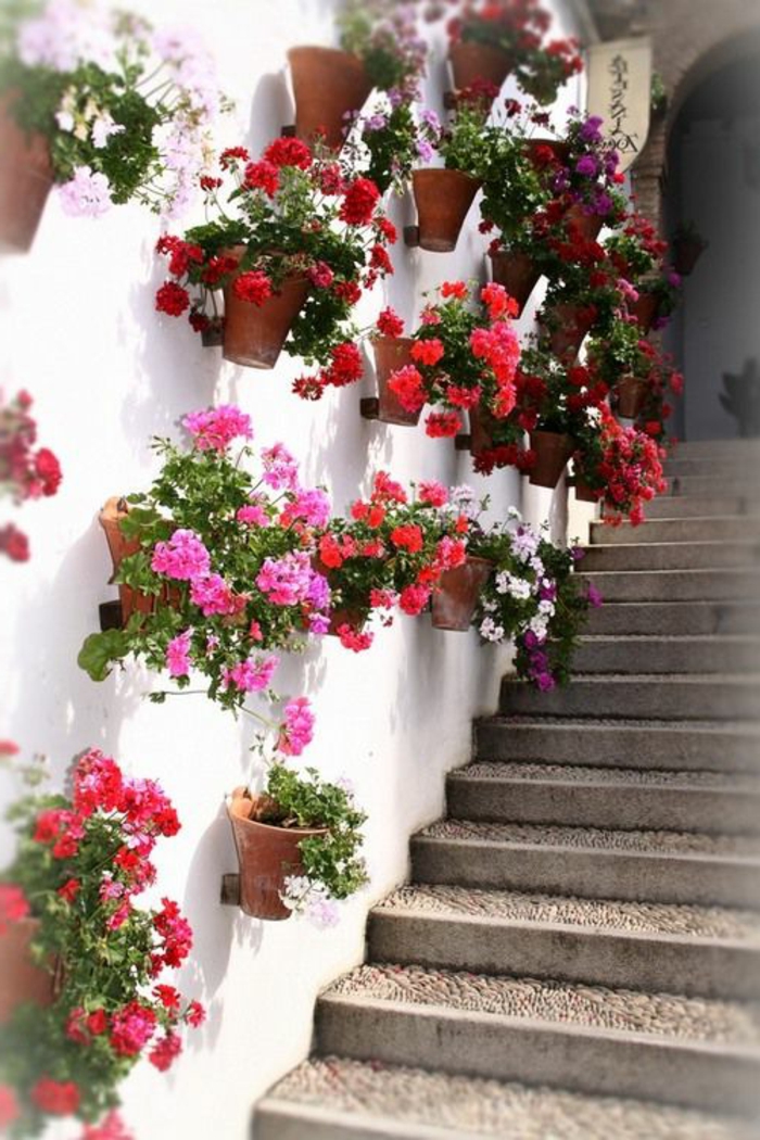 habillage mur exterieur avec des pots de fleurs rouges et roses, idee deco jardin exterieur, décoration murale extérieure, mur blanc, escalier aux marches larges
