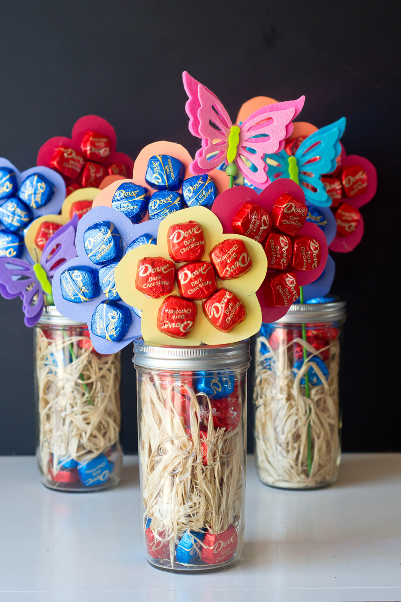 comment faire un bouquet de bonbons collés sur une fleur en papier, bonbons enveloppes rouges et bleues dans un pot en verre et papillons coloré