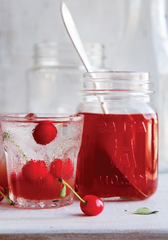 idée limonade rouge aux cerises et eau froide servie dans un pot cocktail avec fruits et herbes fraîches