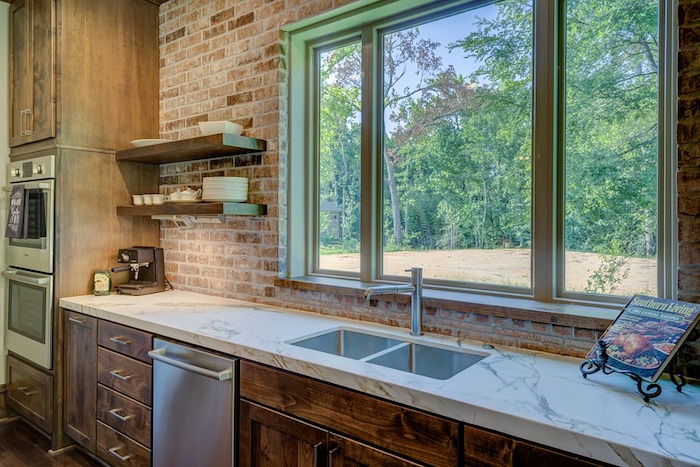 exemple de cuisine tendance 2018 avec mur en briques et meuble cuisine bas avec colonne en bois