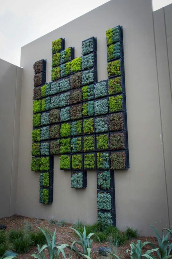 culture verticale sur une cloison de jardin en couleur blanc crème, composition de multiples panneaux de petite taille avec des plantes dans différentes nuances du vert, mur vegetal en palette,mur végétalisé 