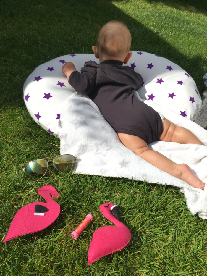 deco exotique, accessoire flamant rose, jouet pour bébé, deco flamant rose, flamants en tissu cousus, bébé couché sur une couverture sur une pelouse verte 