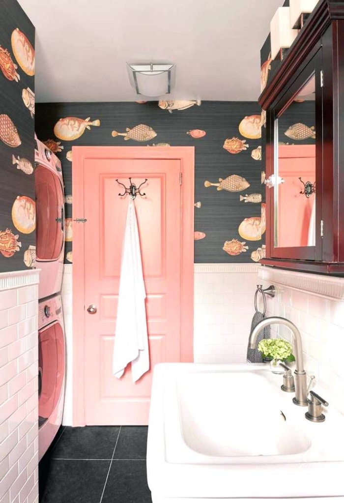 une salle de bains vintage remis au goût du jour grâce à la combinaison inattendue d'un papier peint motif poissons et d'une porte interieur bois avec le carrelage métro