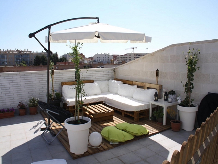 idée comment transformer une terrasse ou balcon avec mobilier en bois recyclé et plantes vertes, modèle de canapé d'angle 