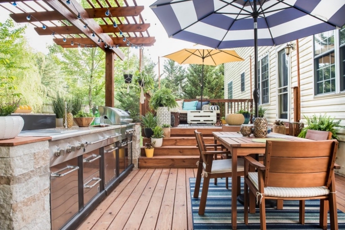 jolie décoration d'extérieur avec parasol colorés et meubles de jardin en bois foncé, modèle de cuisine en acier inox
