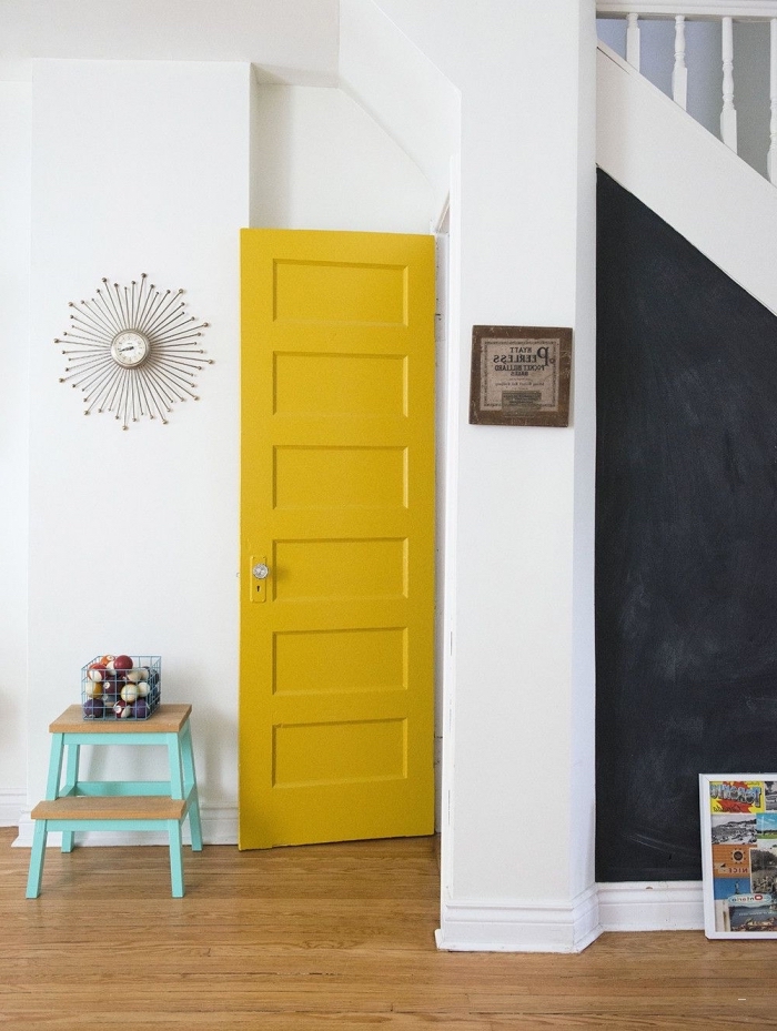 hall d'entrée original dans lequel on a crée des points colorés distincts, la porte interieur peinte en jaune et l'espace sous-escalier en peinture ardoise créent un effet de contraste avec les murs blancs