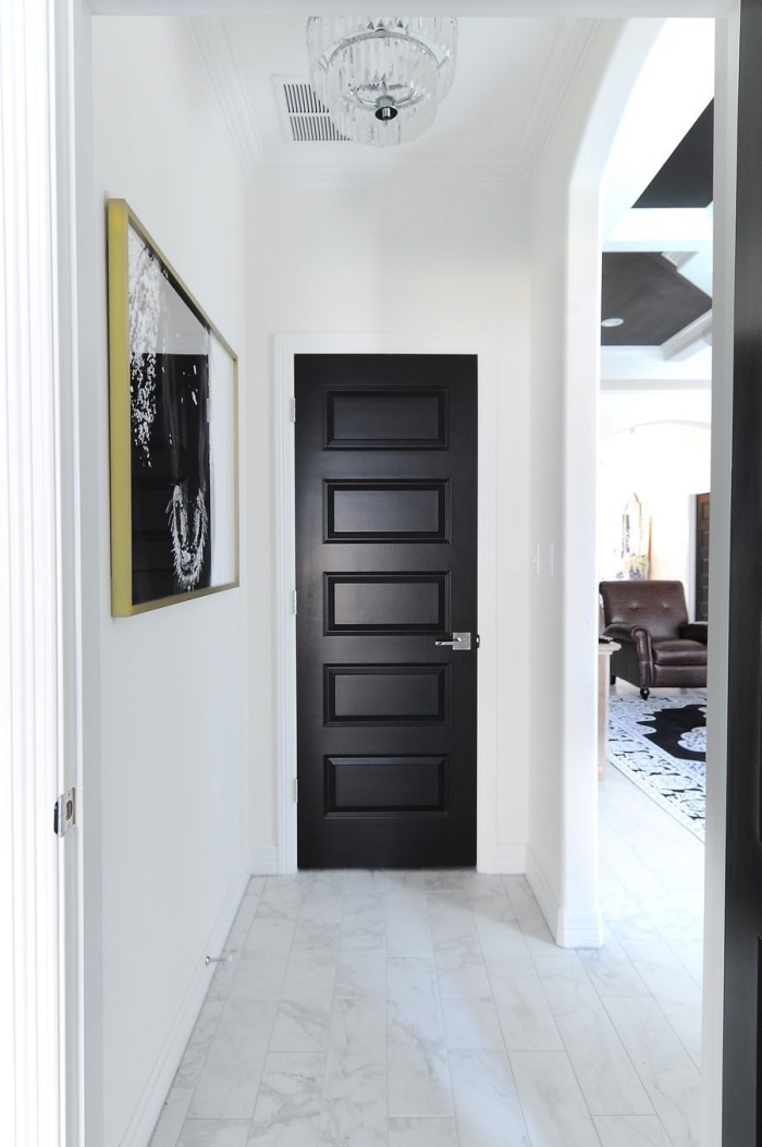 une porte d'intérieur en noir mat et une photo encadrée noir et blanc dynamise l'ambiance monochrome du couloir