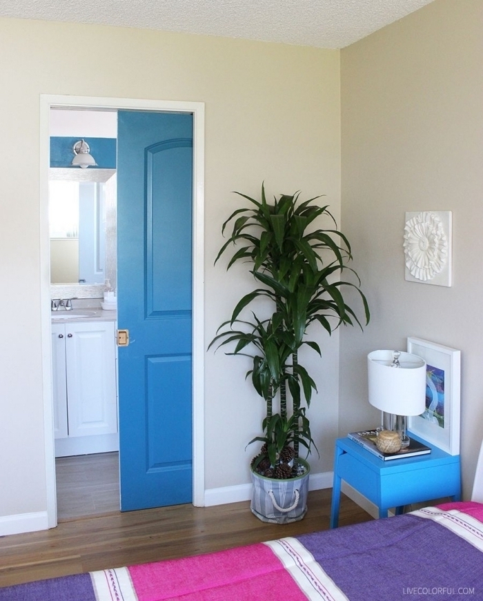 une porte d'intérieur peinte de même couleur bleu marine que la table de chevet, qui apporte du dynamisme à la chambre à coucher en tons neutres