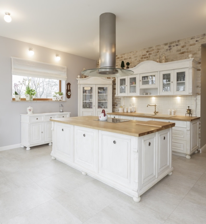 idée décoration dans une cuisine bois blanc avec pan de mur en revêtement papier peint design briques et carrelage sol gris clair
