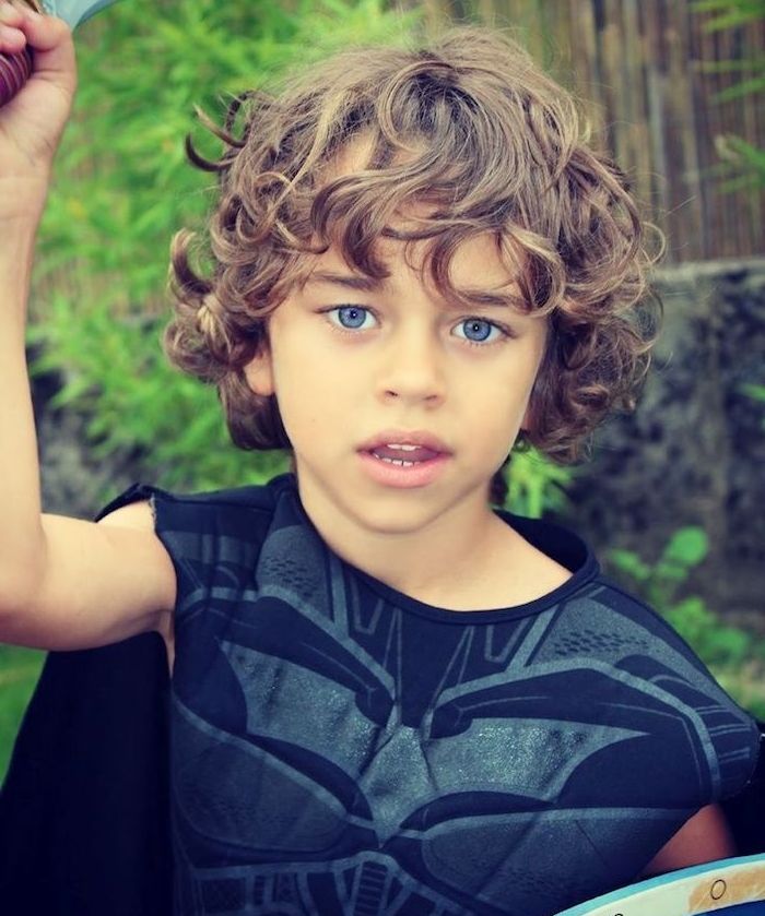 coupe cheveux enfant garçon aux boucles naturelles avec une longue frange sur le front, des yeux bleus