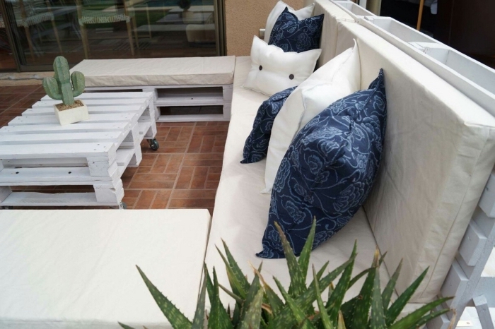 coin extérieur au carrelage de sol marron aménagé avec meuble de palettes blanc, table basse en palette avec cactus