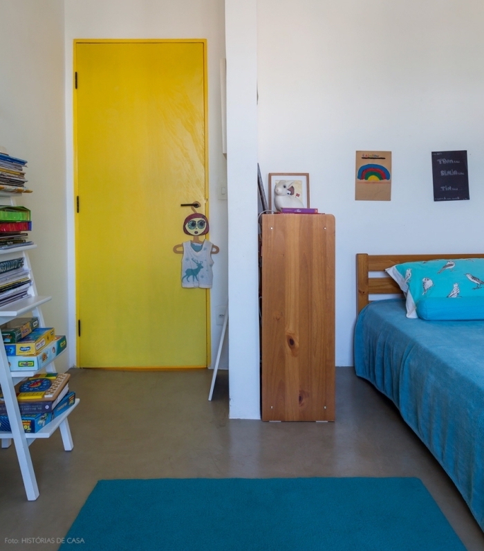 une porte chambre d'enfant peinte en jaune fluo qui dynamise l'intérieur blanc de paire avec les touches de bleu sur le tapis et le linge de lit