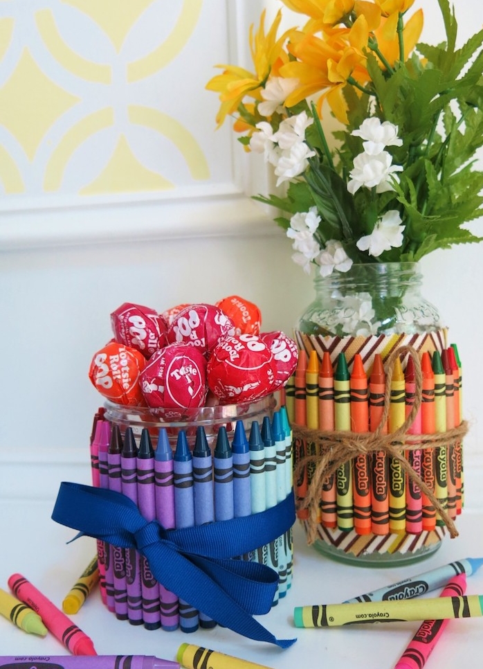 vase ou récipient bonbons avec sucettes dans un bocal en verre décoré de crayons en couleur et ruban, cadeau merci maitresse simple a fabriquer soi meme