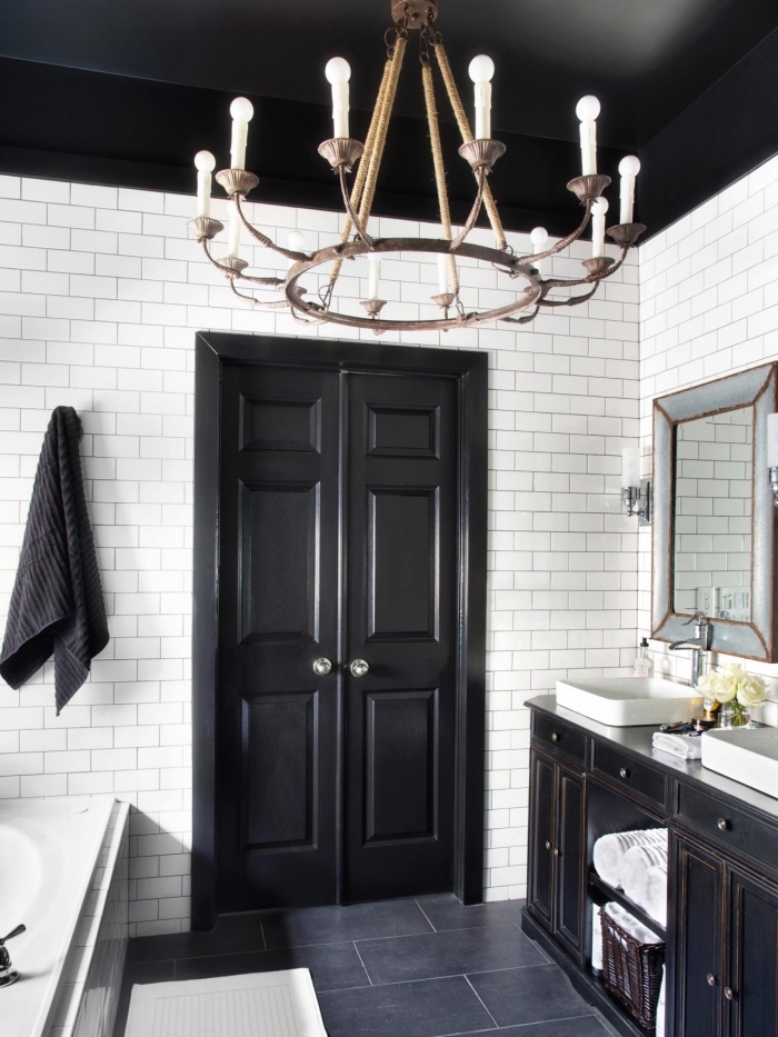 une salle de bains en total look noir et blanc avec une porte interieur double peint en noir en joli contraste avec le carrelage métro