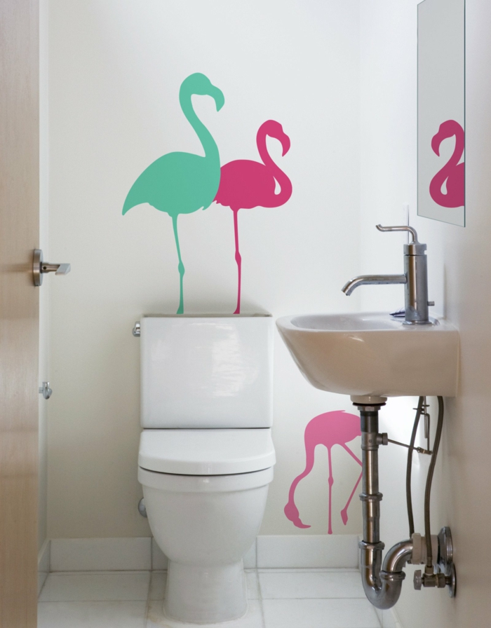 deco tropicale, meubles sanitaires blancs, déco flamant rose, motif feuillage tropical, trois flamants peints sur le mur blanc derrière le meuble de wc,, en couleur vert menthe, en rose et en fuchsia
