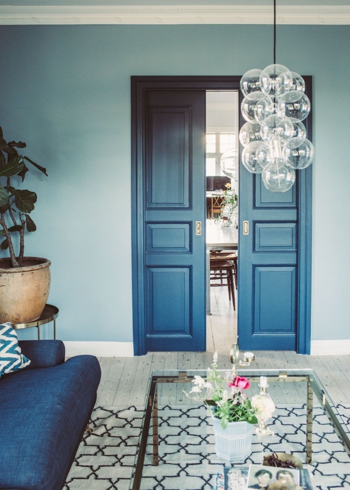 une ambiance élégante et chic dans ce salon bleu où la porte interieure a été repeinte en nuance plus foncée et profonde du bleu