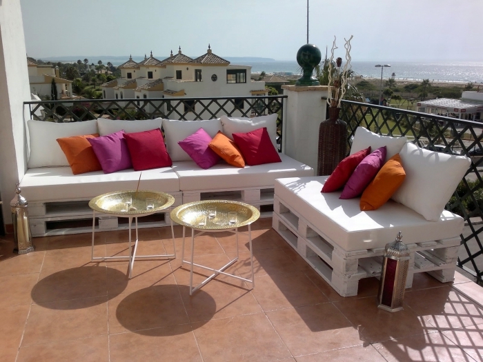 ambiance exotique sur une terrasse au carrelage de sol marron aménagée avec mobilier en palette de bois blanc