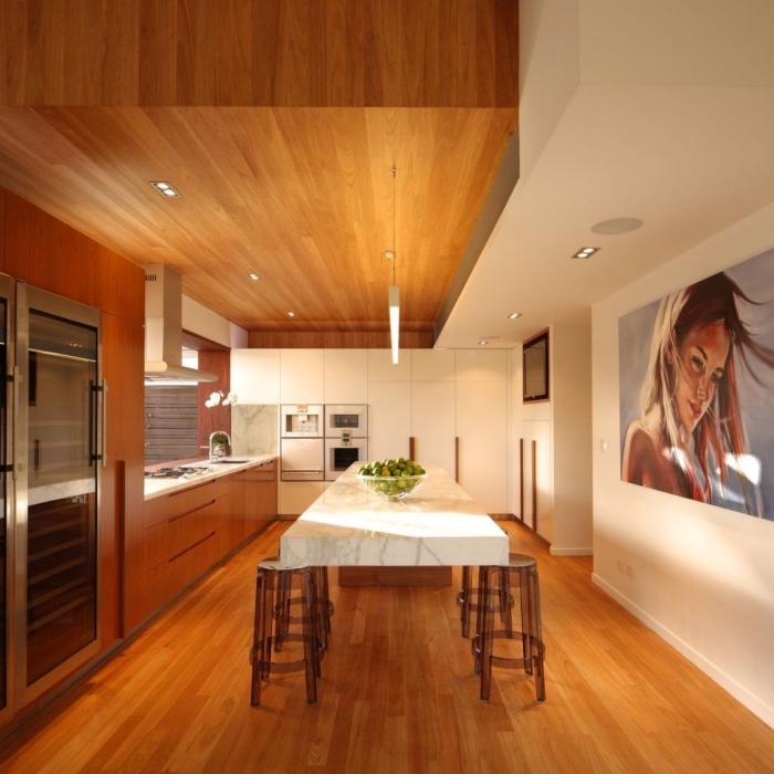 idée comment arranger une cuisine ouverte avec coin à manger, pièce au plafond et parquet bois marron avec pan de mur blanc