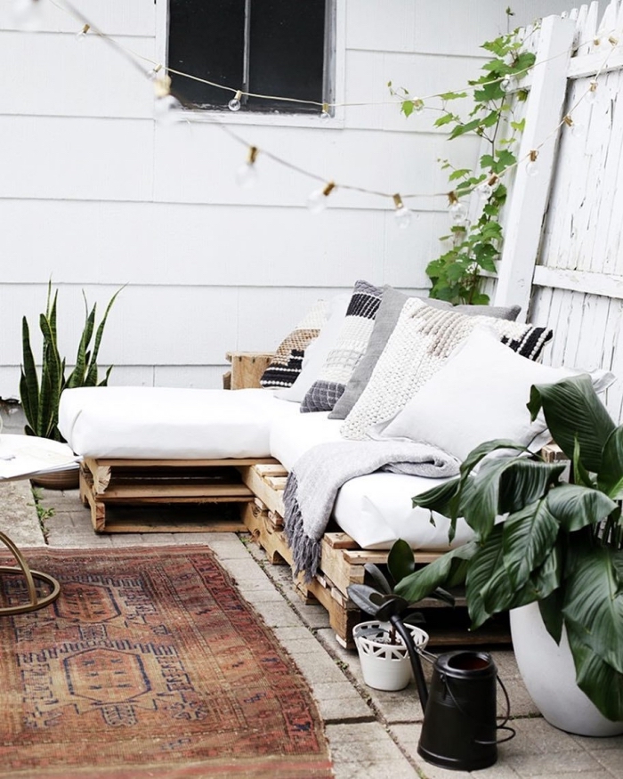 ambiance de style boho chic sur une terrasse ou déco de jardin avec meuble canapé en palette et coussins
