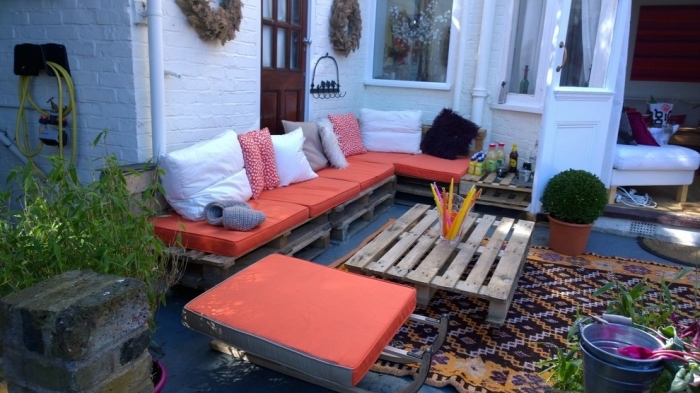 coin de repos dans le jardin avec canapé d'angle DIY en palette et table basse en bois foncé, idée aménagement extérieur