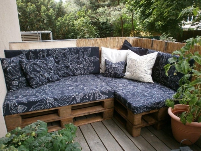 potager sur une terrasse en palette avec meuble d'angle couvert de coussins bleus aux motifs feuilles blancs