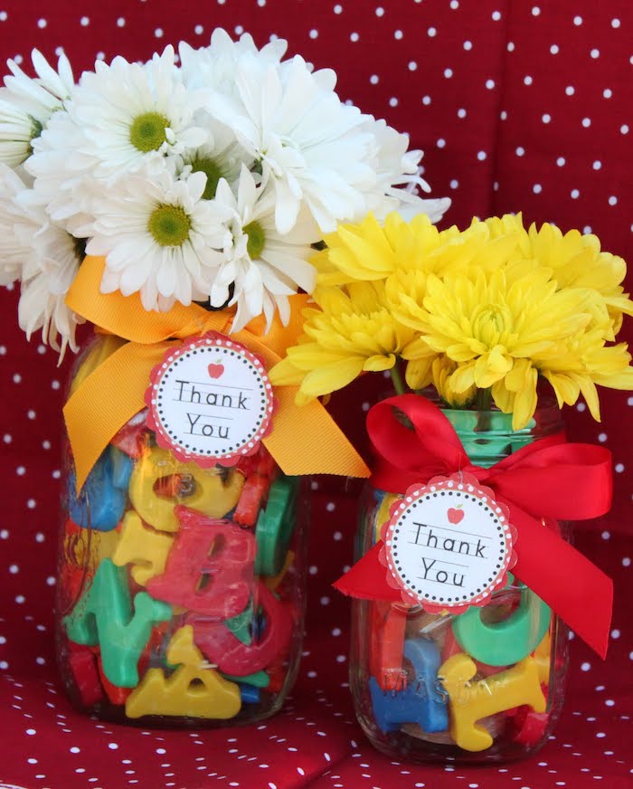 pot en verre rempli de lettres alphabet en plastique avec décoration de ruban et étiquette cadeau, bouquet de fleurs blanches et jaunes